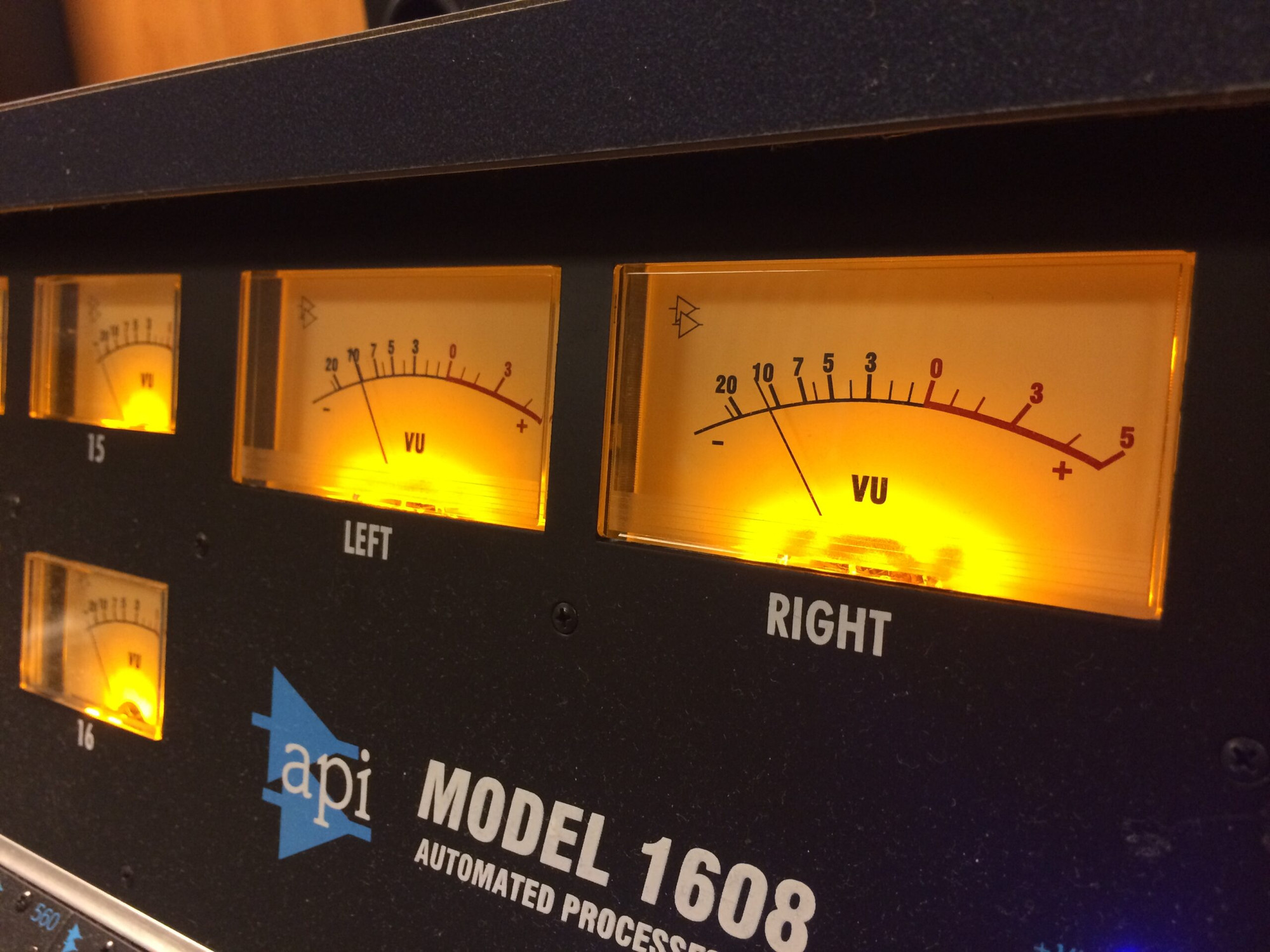 API 1608 recording console VU meter bridge — needle meters glowing above the mixing board